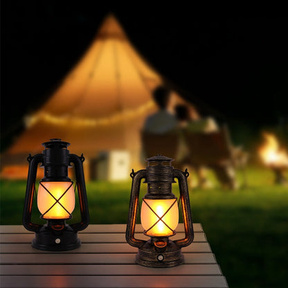 Two lit lanterns on a wooden surface with a blurred background of a campsite.